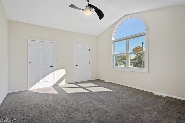 unfurnished bedroom with ceiling fan, dark carpet, and lofted ceiling