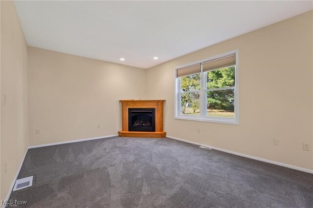 unfurnished living room featuring dark colored carpet