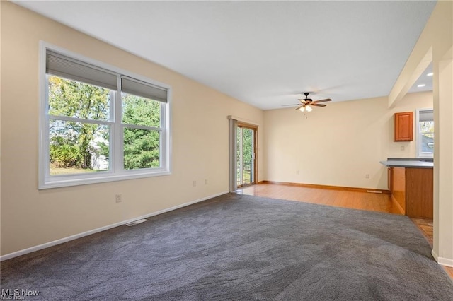 unfurnished living room featuring ceiling fan and light carpet