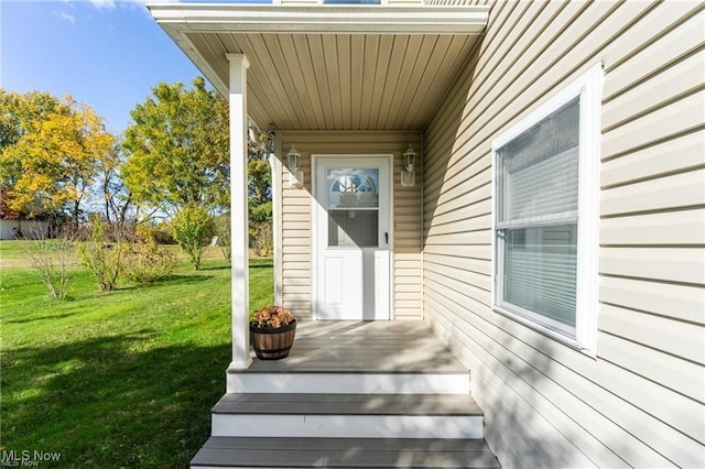 view of exterior entry featuring a lawn