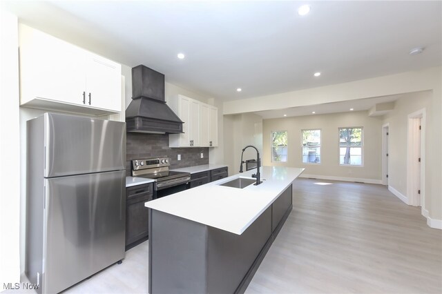 kitchen featuring white cabinets, sink, a center island with sink, stainless steel appliances, and custom range hood