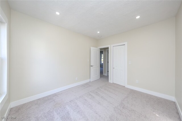 unfurnished bedroom with a textured ceiling and light colored carpet