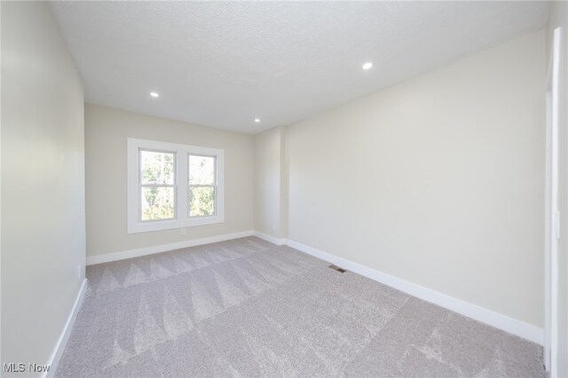 unfurnished room with light carpet and a textured ceiling