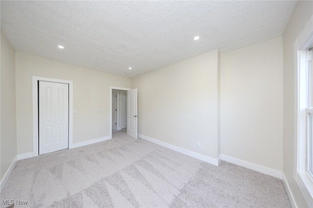 empty room featuring light carpet and a textured ceiling