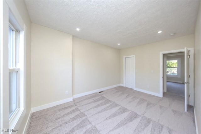 spare room with a textured ceiling and light colored carpet