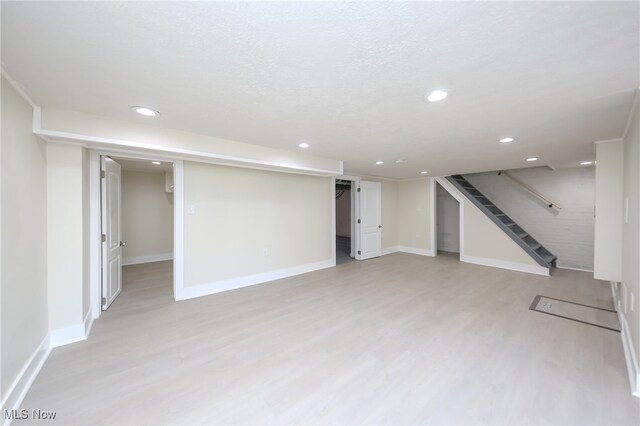 basement with light hardwood / wood-style floors and a textured ceiling