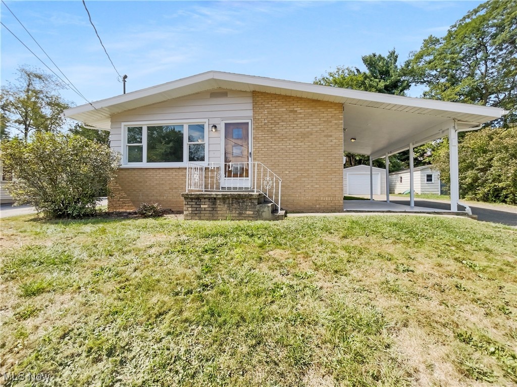 view of front of house with an outbuilding, a carport, a garage, and a front yard