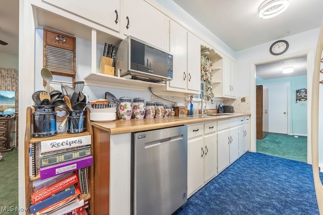 kitchen featuring dark carpet, white cabinets, sink, tasteful backsplash, and stainless steel appliances