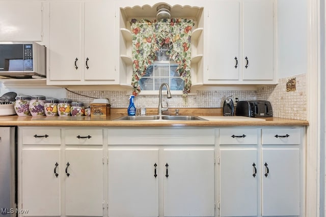 kitchen with backsplash, sink, stainless steel appliances, and white cabinets