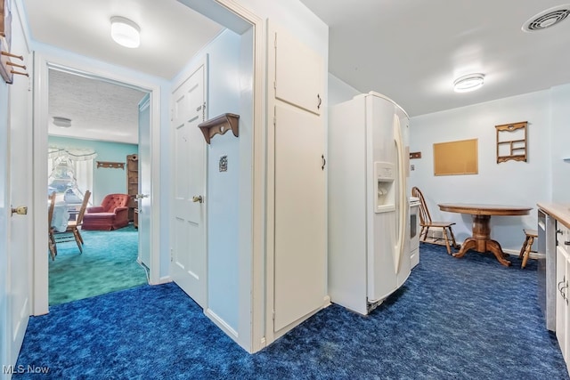 hallway with dark carpet and a textured ceiling