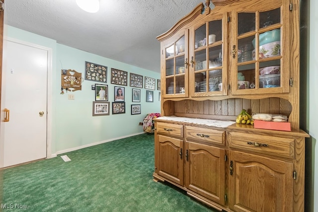 kitchen with dark carpet and a textured ceiling