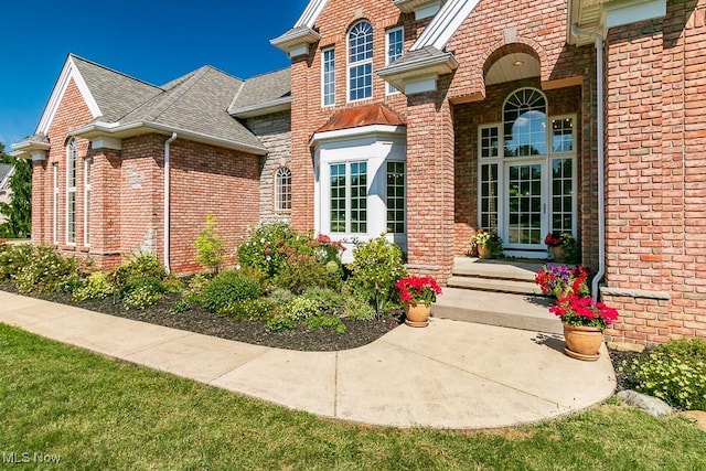 property entrance with a shingled roof and brick siding