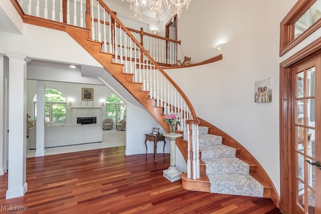 staircase with an inviting chandelier, a towering ceiling, and hardwood / wood-style flooring