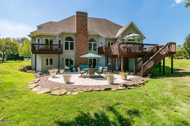 rear view of property featuring a lawn, a patio area, a wooden deck, and a chimney