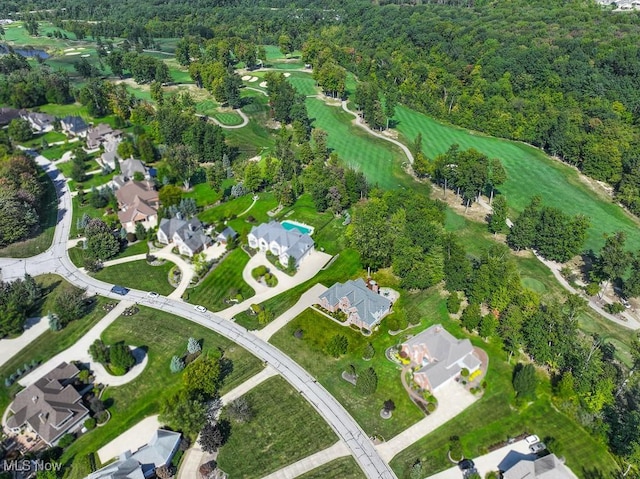 drone / aerial view featuring a forest view, view of golf course, and a residential view