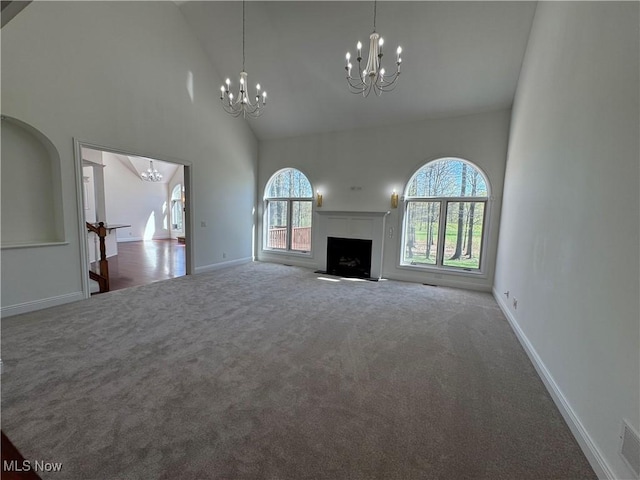 unfurnished living room featuring an inviting chandelier, carpet floors, a healthy amount of sunlight, and high vaulted ceiling