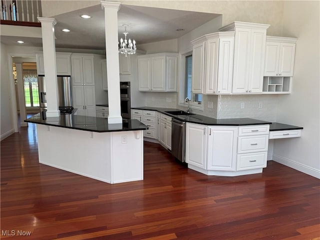kitchen featuring decorative backsplash, dark wood-style flooring, ornate columns, a sink, and stainless steel appliances
