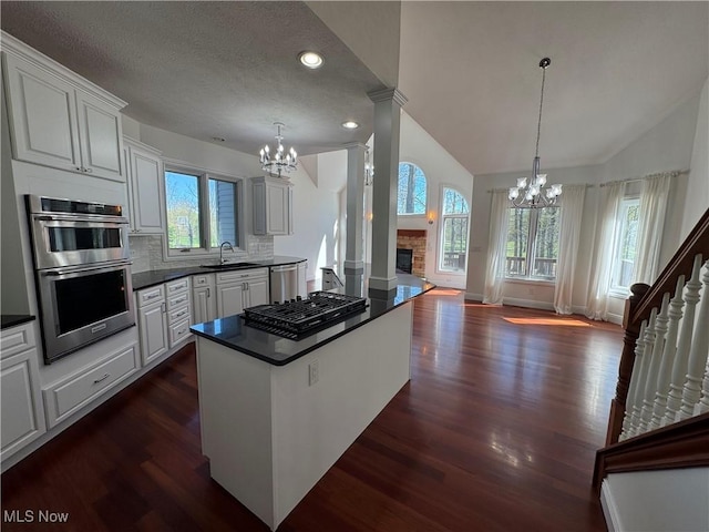 kitchen with an inviting chandelier, dark countertops, dark wood-type flooring, a sink, and appliances with stainless steel finishes