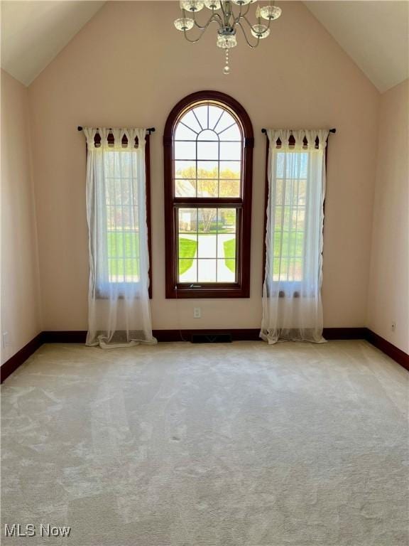 spare room featuring visible vents, vaulted ceiling, carpet floors, baseboards, and a notable chandelier