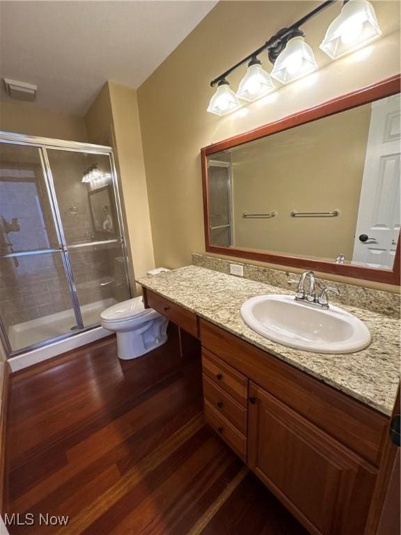 full bathroom featuring toilet, a shower stall, wood finished floors, and vanity