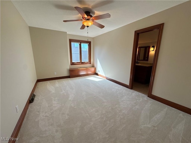 carpeted spare room with baseboards, ceiling fan, and visible vents