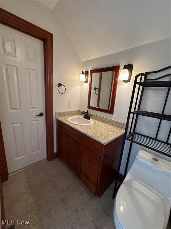 bathroom with vanity, tile patterned floors, and lofted ceiling