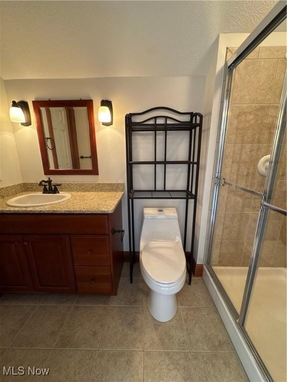 bathroom with toilet, tile patterned floors, a shower stall, and vanity