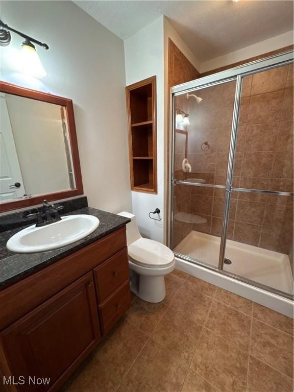 full bath featuring vanity, tile patterned floors, a stall shower, and toilet