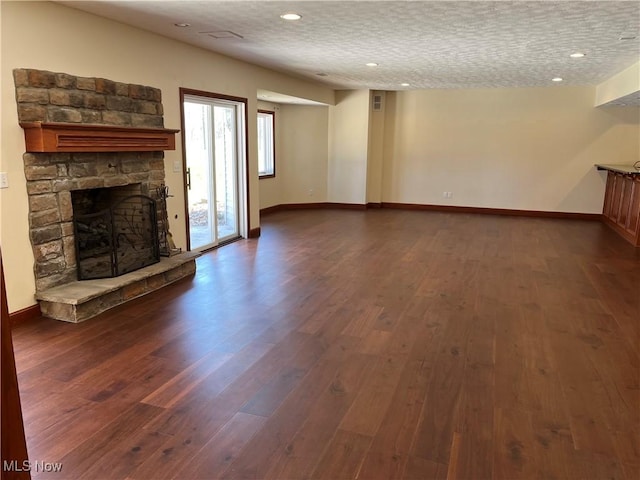 unfurnished living room with dark wood-style flooring, a fireplace, baseboards, recessed lighting, and a textured ceiling