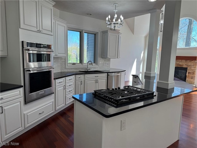 kitchen featuring stainless steel appliances, dark countertops, dark wood finished floors, and a sink