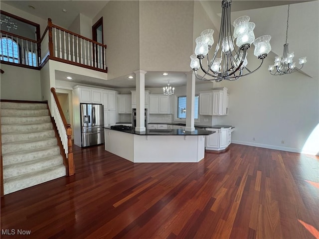 kitchen featuring dark wood-style flooring, dark countertops, appliances with stainless steel finishes, a chandelier, and a high ceiling