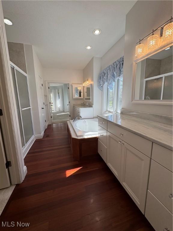 bathroom with vanity, recessed lighting, a shower stall, wood finished floors, and a garden tub