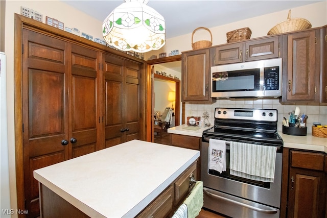 kitchen featuring hanging light fixtures, a center island, stainless steel appliances, and tasteful backsplash