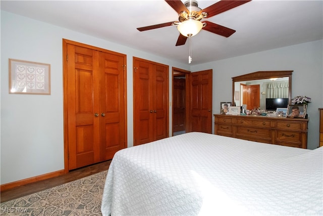 bedroom featuring hardwood / wood-style flooring, ceiling fan, and multiple closets