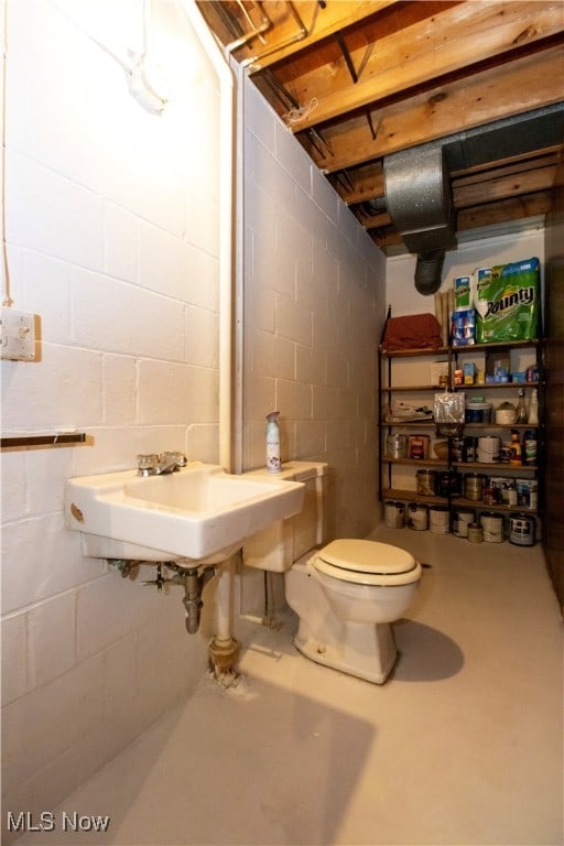 bathroom featuring concrete flooring, sink, and toilet