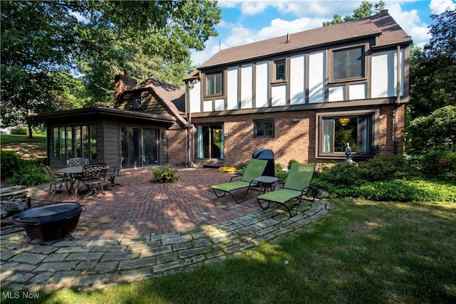 back of property with a yard, a patio area, and a fire pit