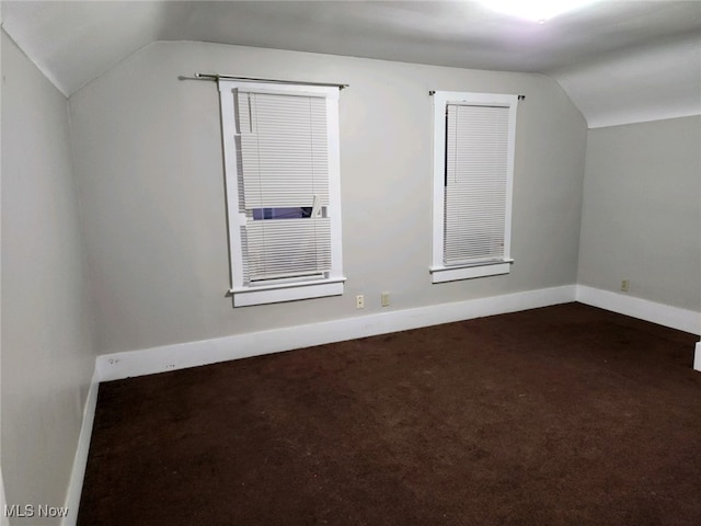 bonus room with lofted ceiling and dark colored carpet