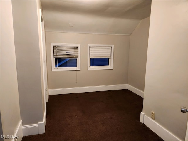 empty room featuring vaulted ceiling and dark carpet