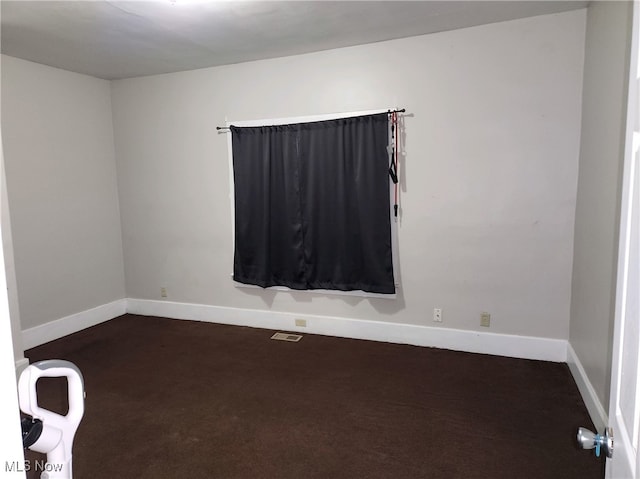 spare room featuring dark carpet