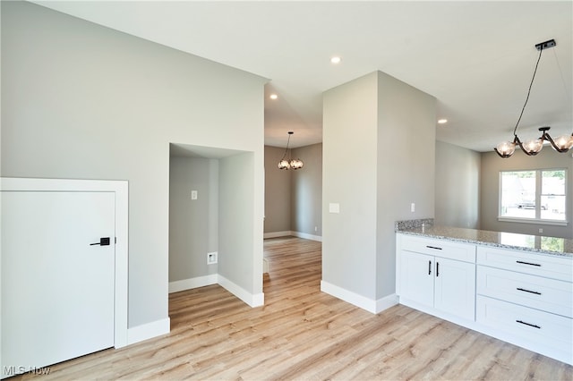 kitchen featuring light stone counters, hanging light fixtures, a chandelier, white cabinetry, and light hardwood / wood-style floors