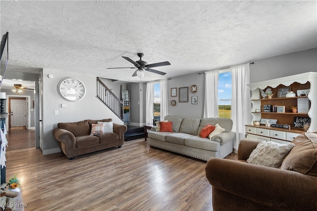 living room featuring wood-type flooring, ceiling fan, and a textured ceiling