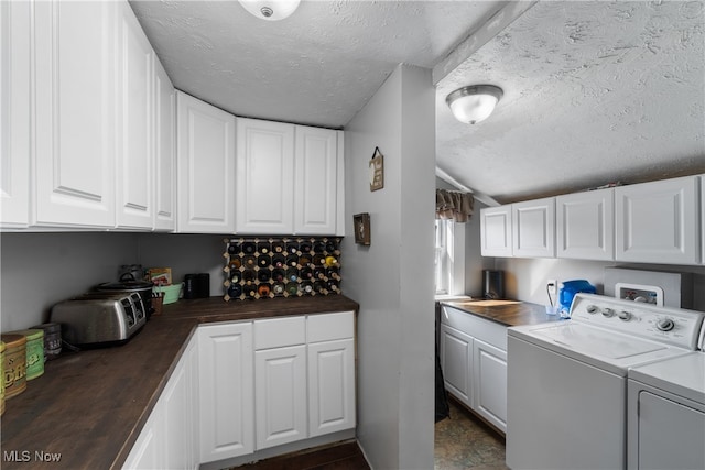 clothes washing area featuring cabinets, a textured ceiling, and separate washer and dryer