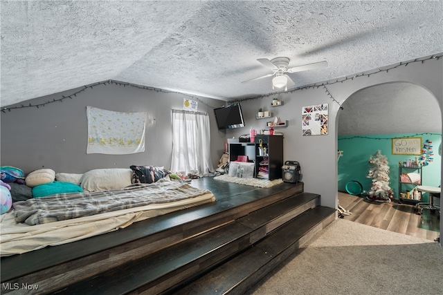 bedroom featuring carpet floors, a textured ceiling, vaulted ceiling, and ceiling fan