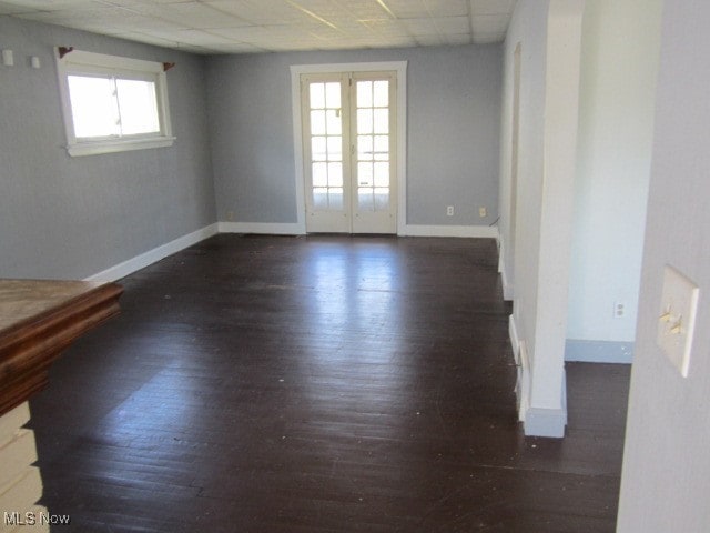 unfurnished room featuring french doors, a drop ceiling, and dark hardwood / wood-style flooring