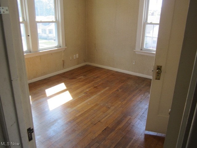 spare room with a healthy amount of sunlight and dark wood-type flooring