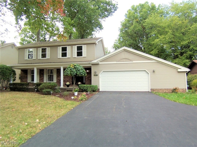 view of front of house with covered porch, a front yard, and a garage