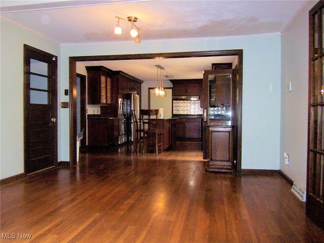 unfurnished living room featuring crown molding, dark hardwood / wood-style flooring, and a notable chandelier