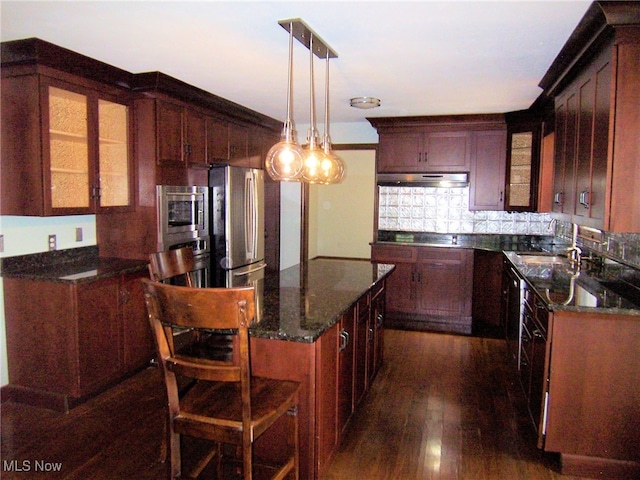 kitchen featuring hanging light fixtures, decorative backsplash, stainless steel appliances, exhaust hood, and dark hardwood / wood-style floors