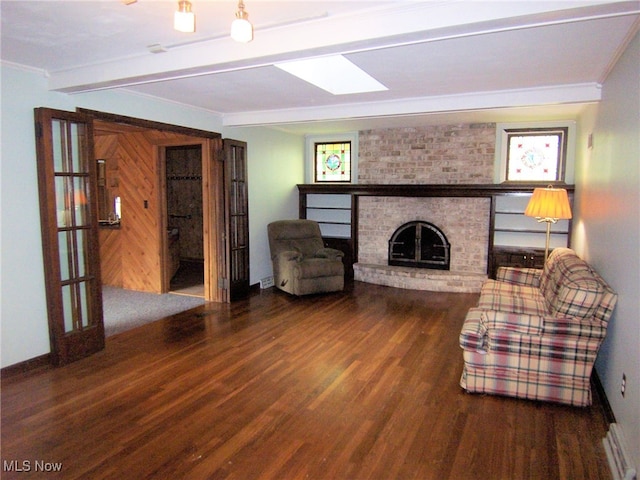 unfurnished living room with a brick fireplace, dark hardwood / wood-style floors, beam ceiling, and crown molding