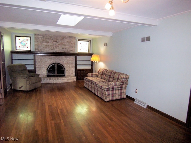 living room featuring beamed ceiling, hardwood / wood-style flooring, a fireplace, and ornamental molding